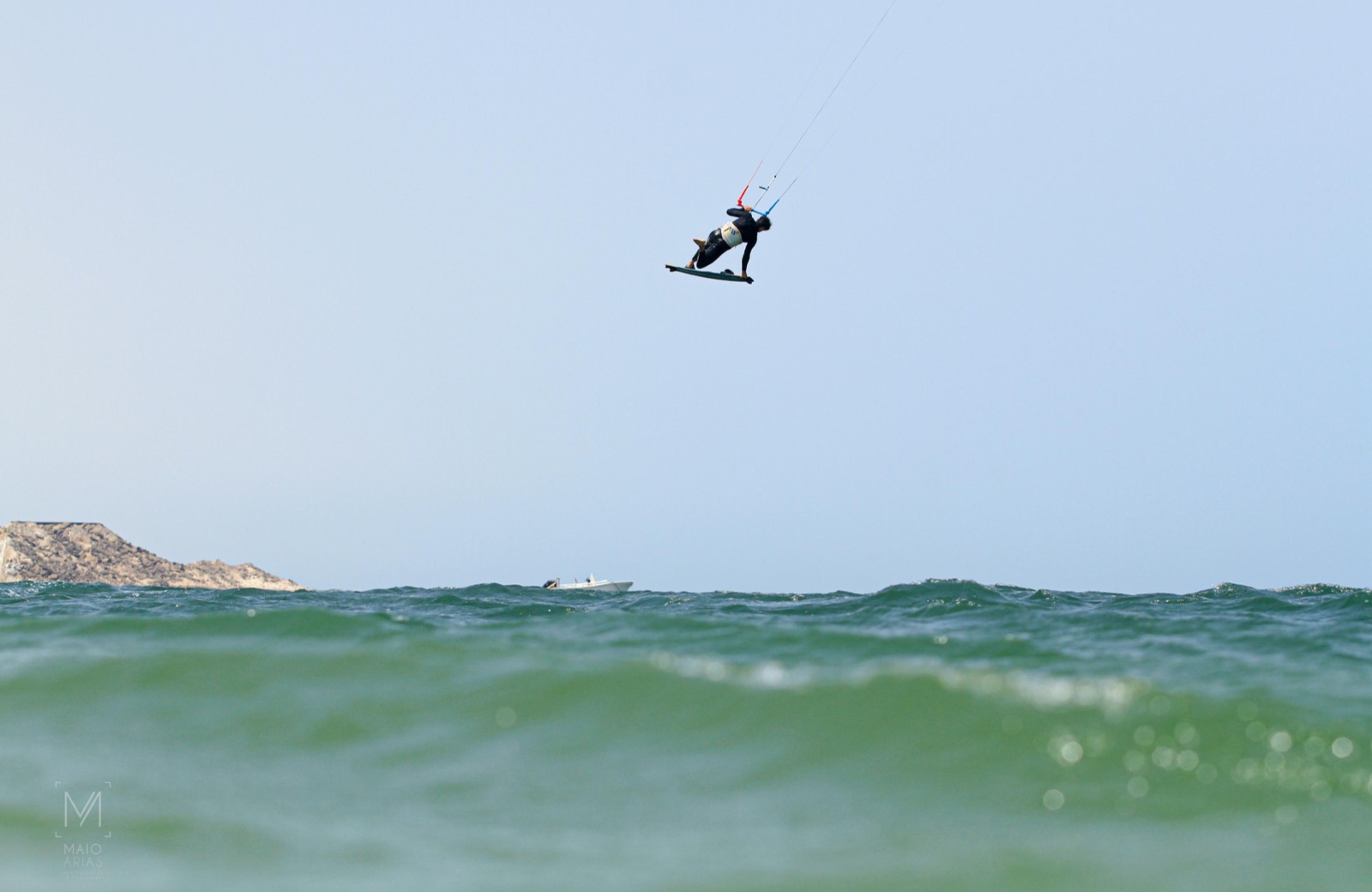 Kitesurfista suspendido en un salto sobre el mar, fotografiado a ras de las olas.